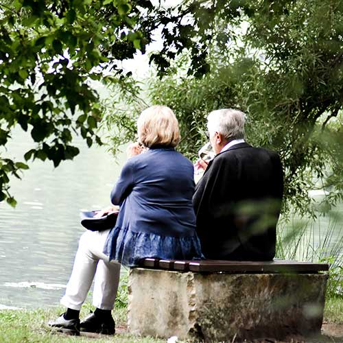 An elderly couple sitting on a bench in a scenic area