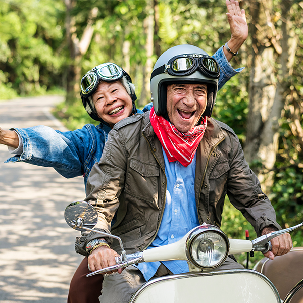 Happy old couple riding on a scooter in the countryside