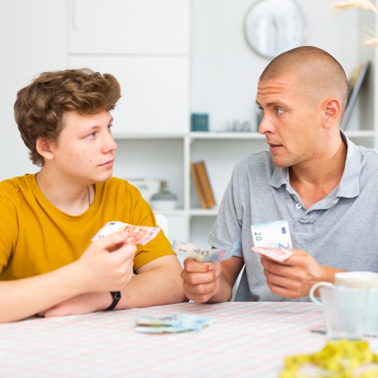 Man and son holding money and having a conversation